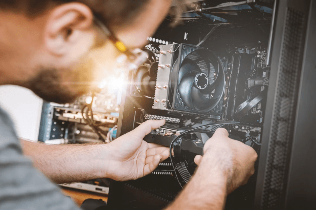 An IT technician performing hardware maintenance inside a computer.