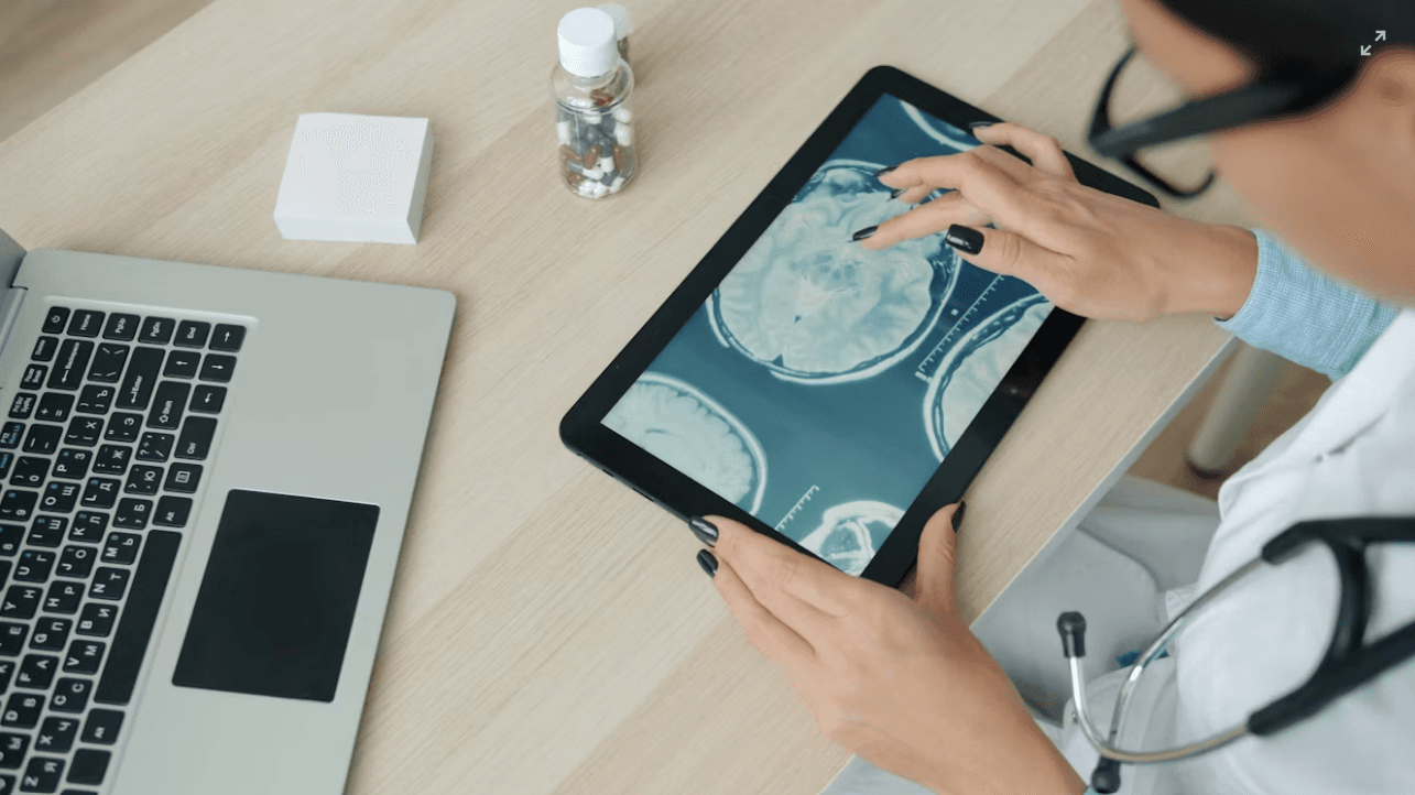 A clinician reviewing medical records and imaging on a tablet at a desk.